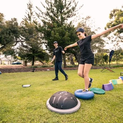 Ability Gym training a person with a disability in a park jumping on equipment